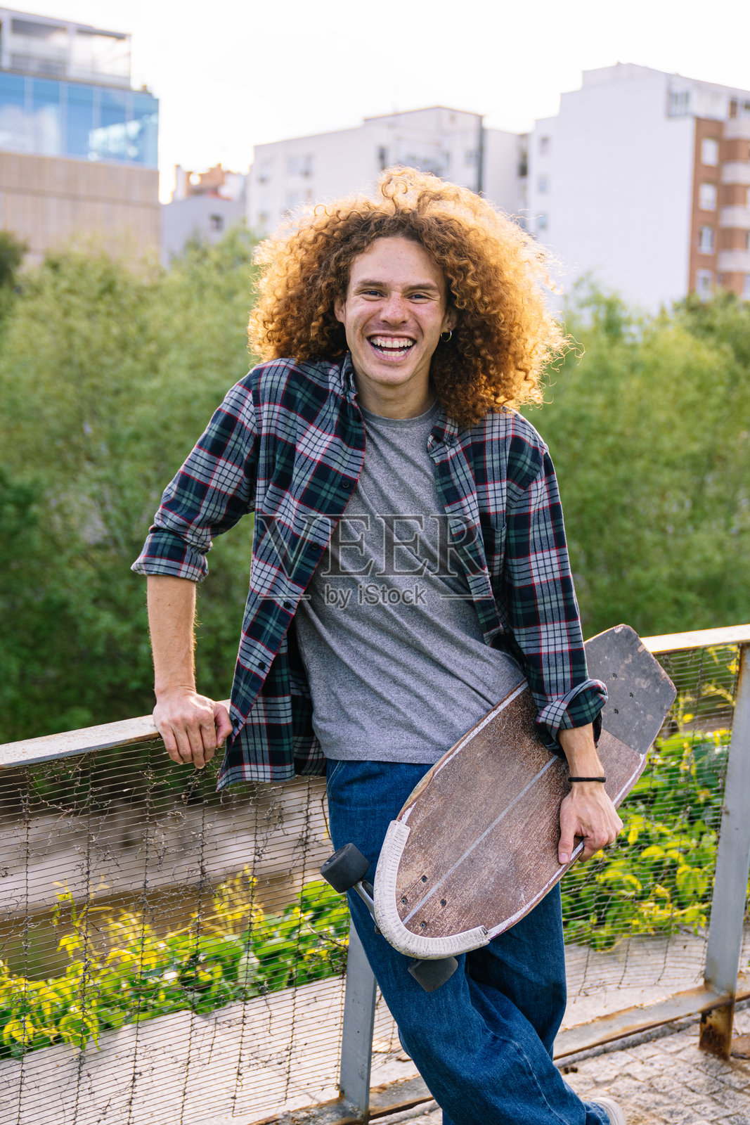 年轻的滑板少年手持长板,面带微笑看向镜头照片摄影图片