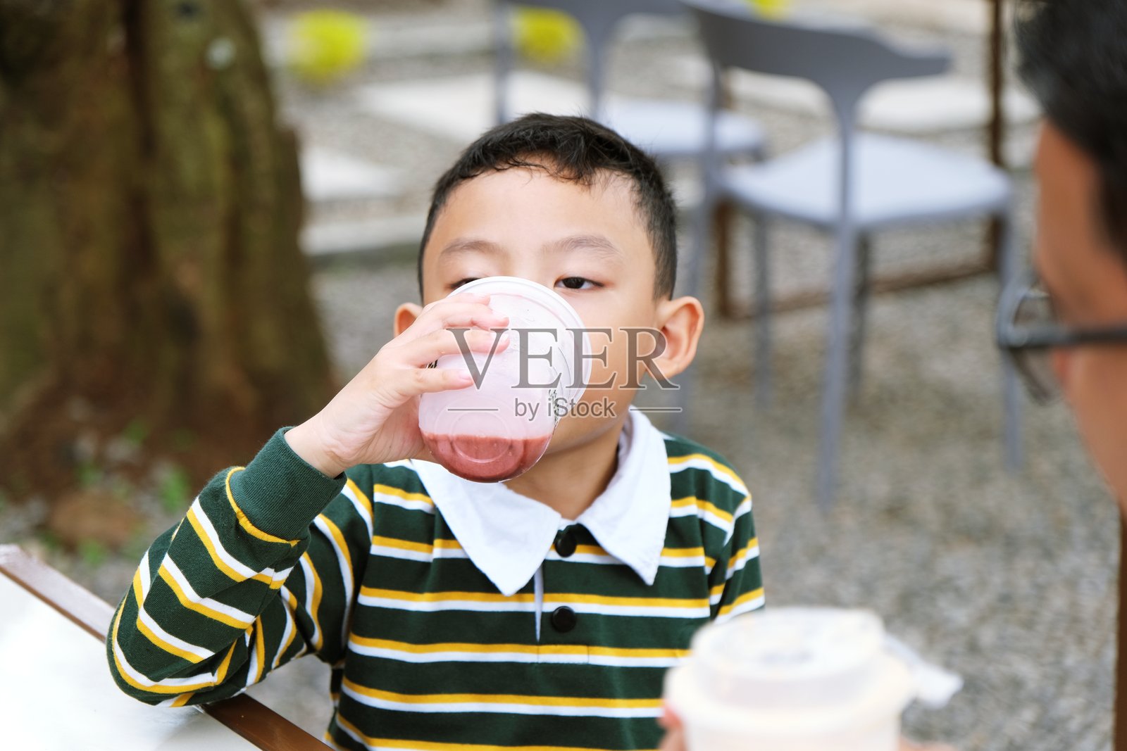 年轻男孩在户外享用草莓奶昔照片摄影图片