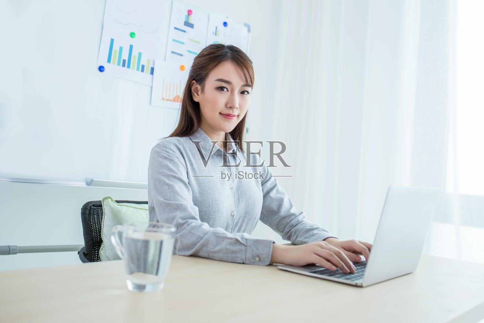 亚洲女性在现代办公室使用笔记本电脑工作照片摄影图片