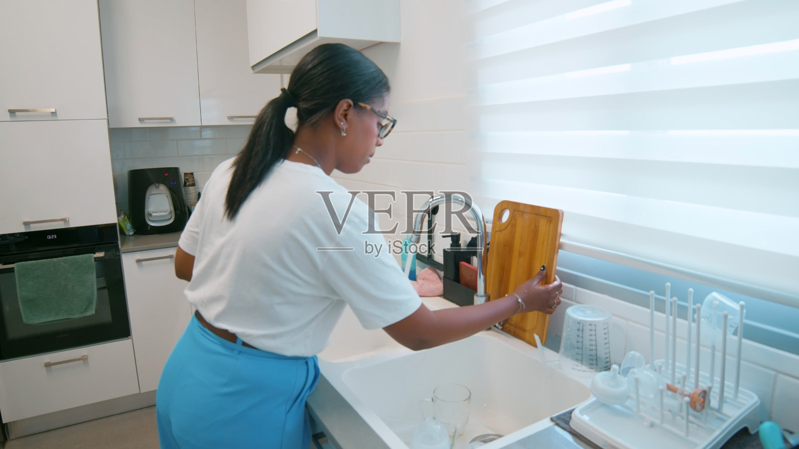 女人在现代厨房里清洗木质切菜板照片摄影图片