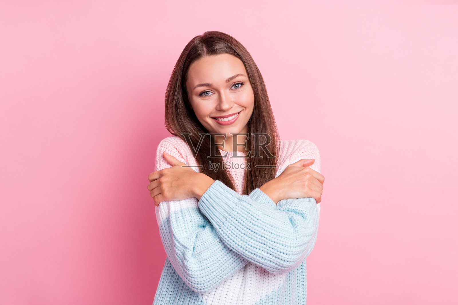 微笑的棕发模特在粉色背景前自我拥抱的照片肖像照片摄影图片