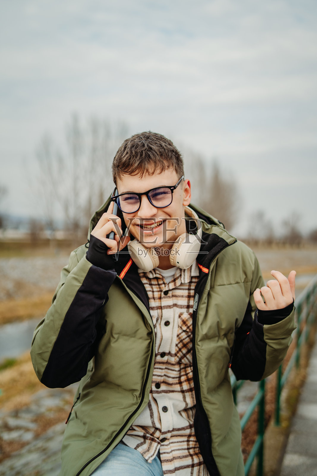 年轻的白人学生微笑着使用智能手机聊天或自拍照片摄影图片