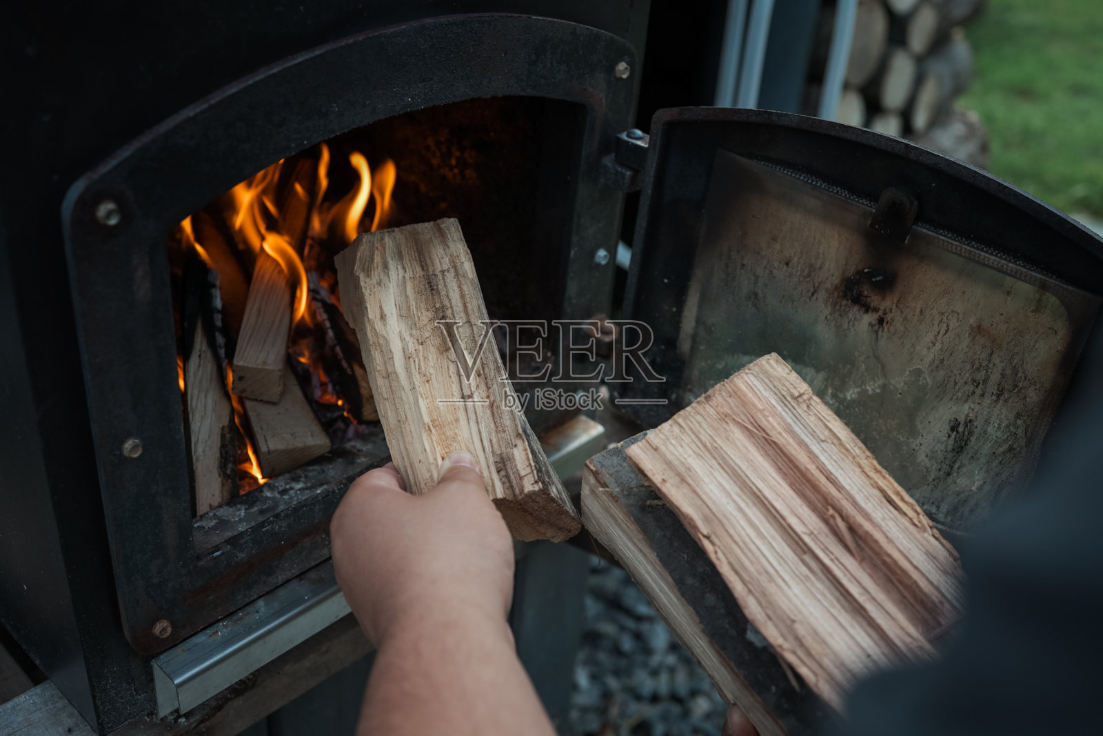 黑色金属炉内的木柴特写,明亮的橙色火焰和闪烁的余烬,营造出温暖而质朴的氛围照片摄影图片