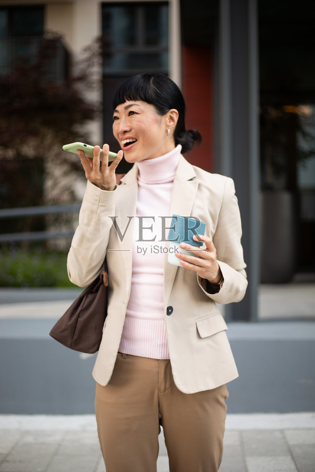女商人在拿着可重复使用的咖啡杯时留下语音留言照片摄影图片