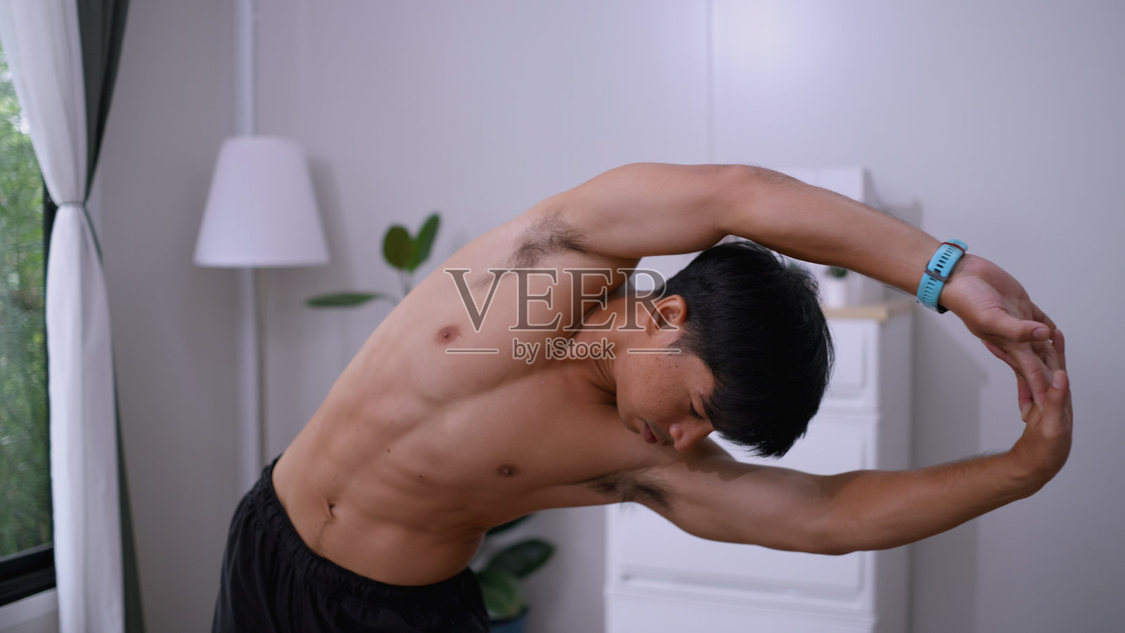 智能家居拉伸 - 男子使用平板电脑上的人工智能来改善柔韧性。照片摄影图片