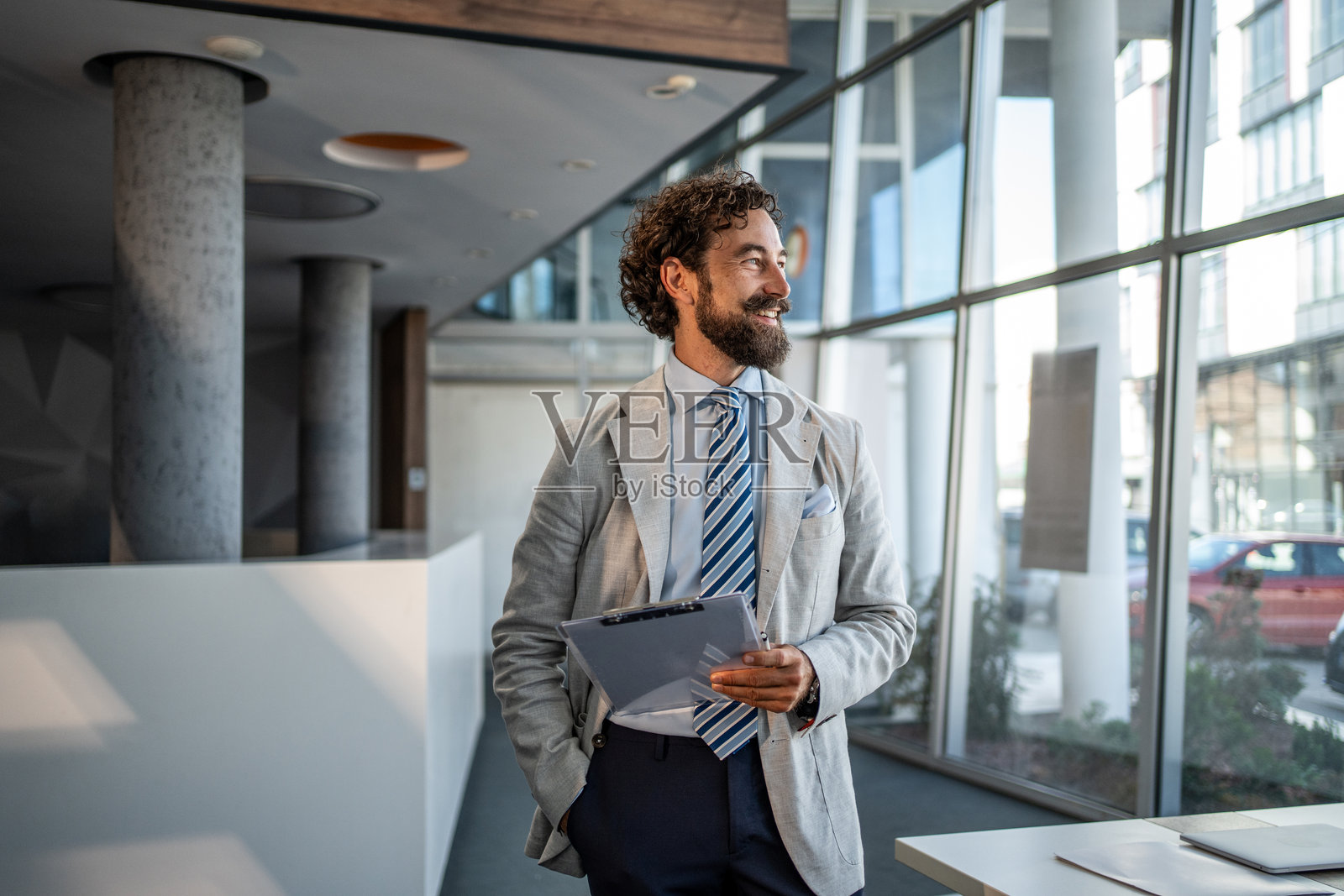 自信的商人在现代办公室里手持夹板微笑照片摄影图片