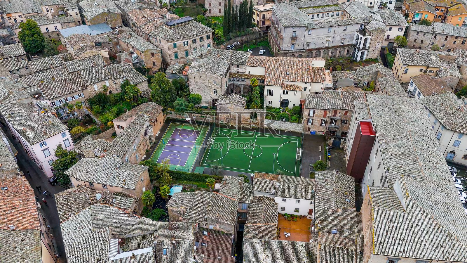 从上方俯瞰意大利翁布里亚地区奥尔维耶托的足球场和篮球场,周围环绕着历史悠久的石建筑,古老建筑中的城市休闲区,旅行与休闲概念照片摄影图片