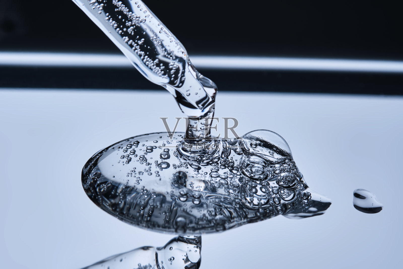 蓝色背景下滴管中的带有刺状物的精华液质地。照片摄影图片