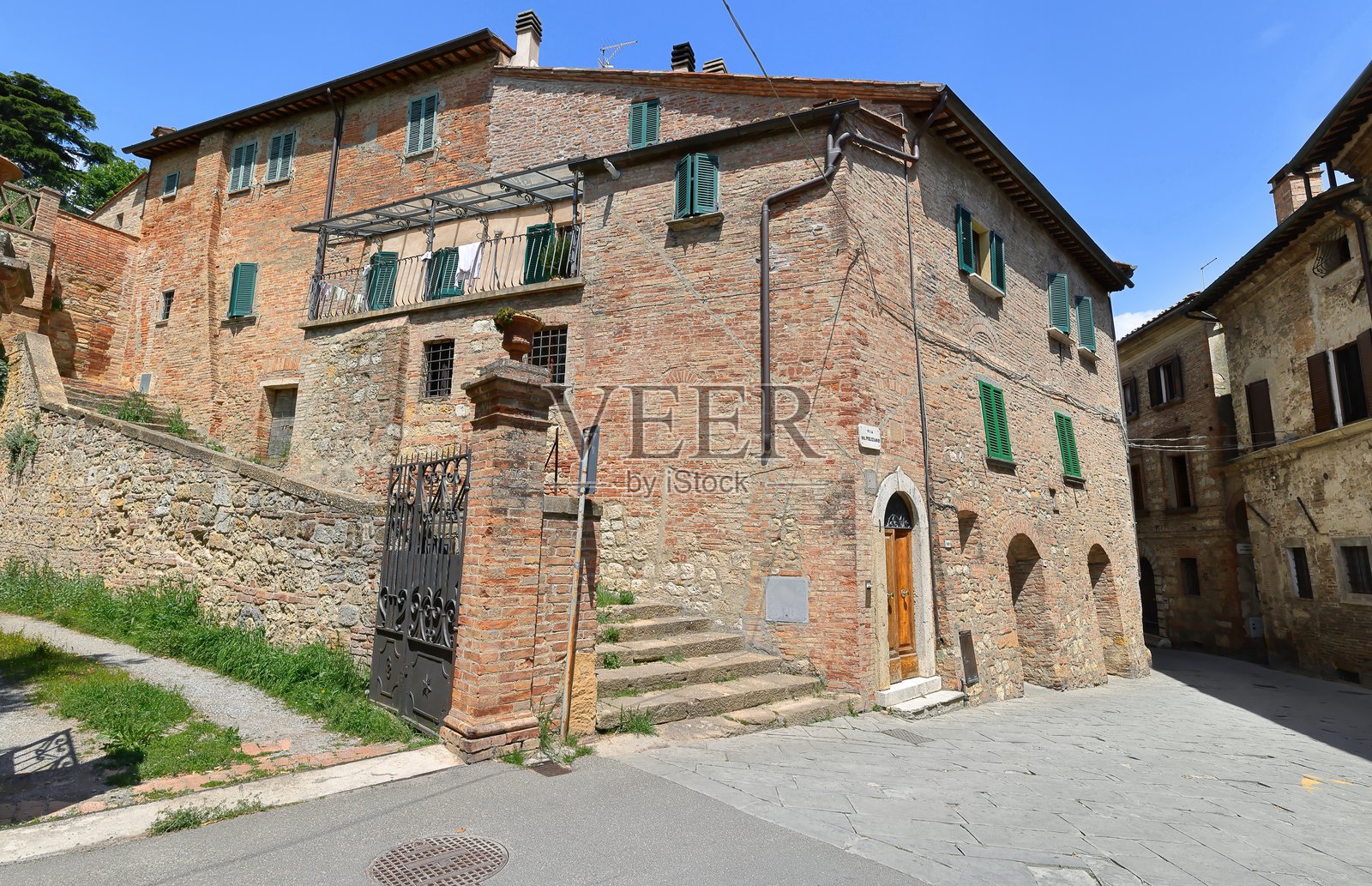 巨大的红砖墙,位于30号Via del Poliziano的拐角建筑,配有绿色木质百叶窗和侧面楼梯。蒙特普尔恰诺-托斯卡纳-意大利-049照片摄影图片