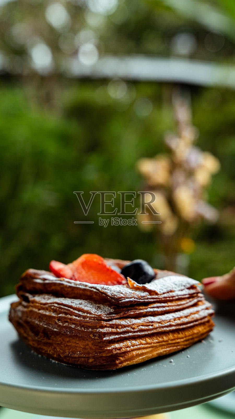 美味的酥皮点心,上面放着新鲜的草莓、蓝莓和糖霜,摆放在盘子里照片摄影图片