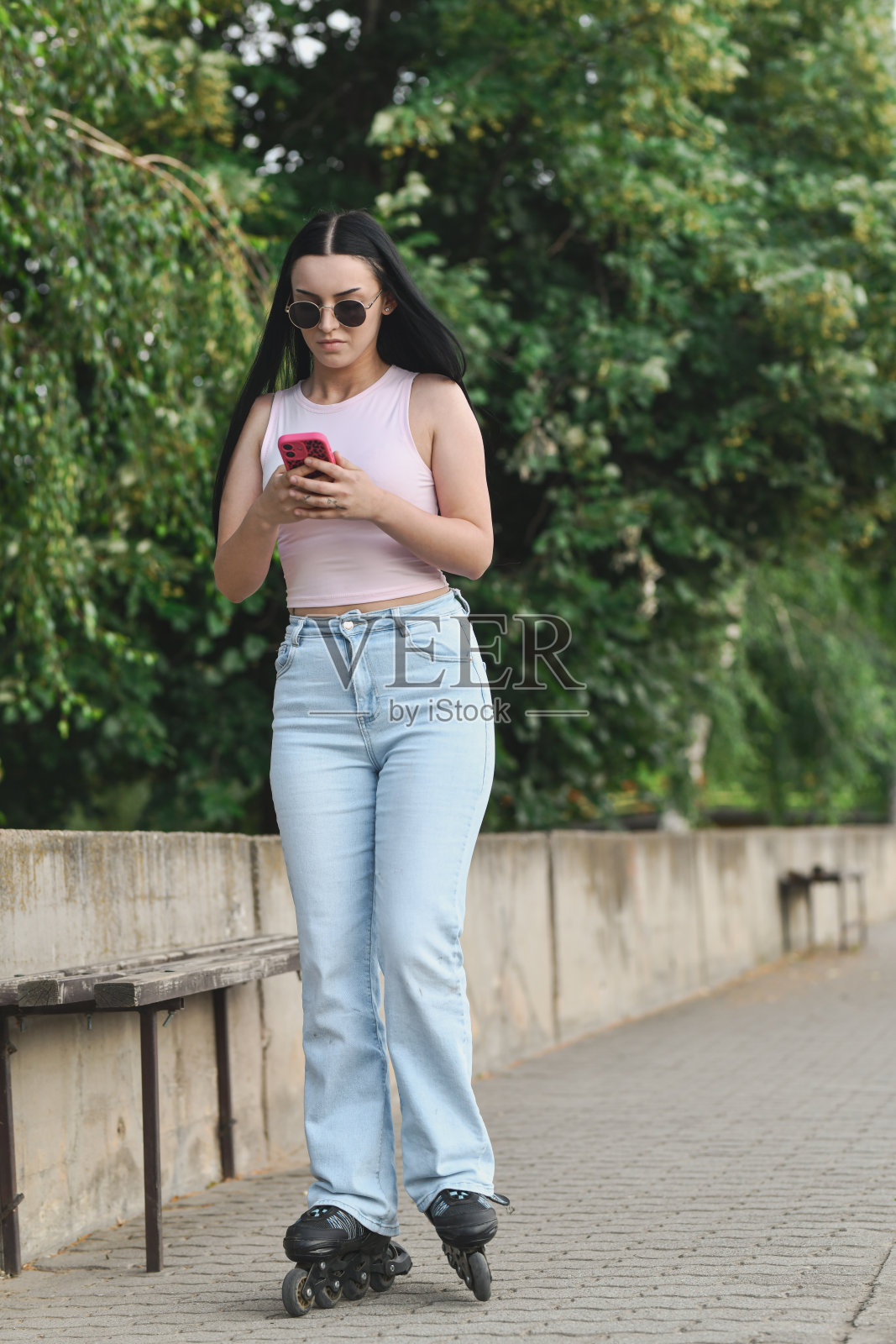 分心的女性在滑板上滑行,同时专注于手机信息照片摄影图片