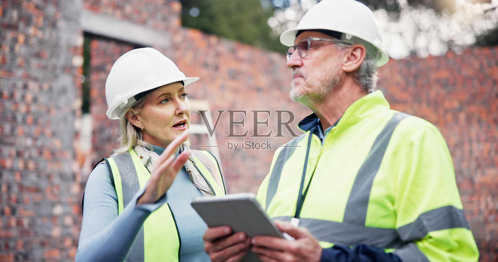 建筑、讨论和同事们使用平板电脑,户外团队合作进行项目管理和应用开发。成熟的男女与科技设备进行数字蓝图的协作与交流。照片摄影图片