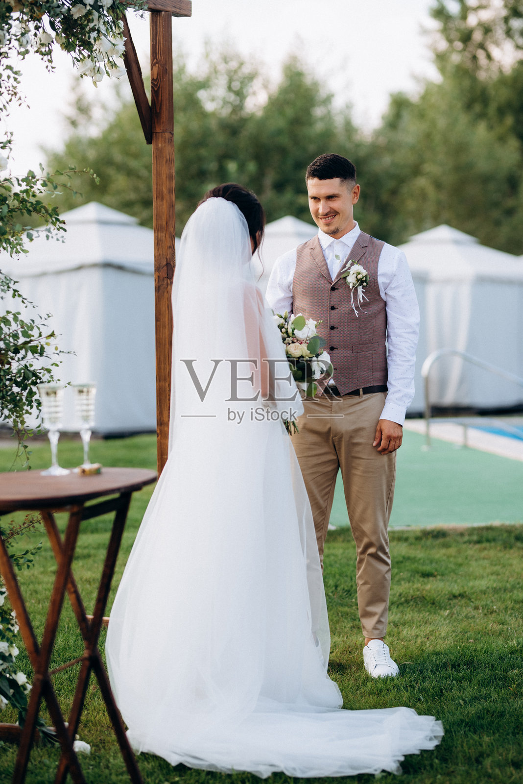 一对年轻情侣在绿草地上的婚礼仪式照片摄影图片