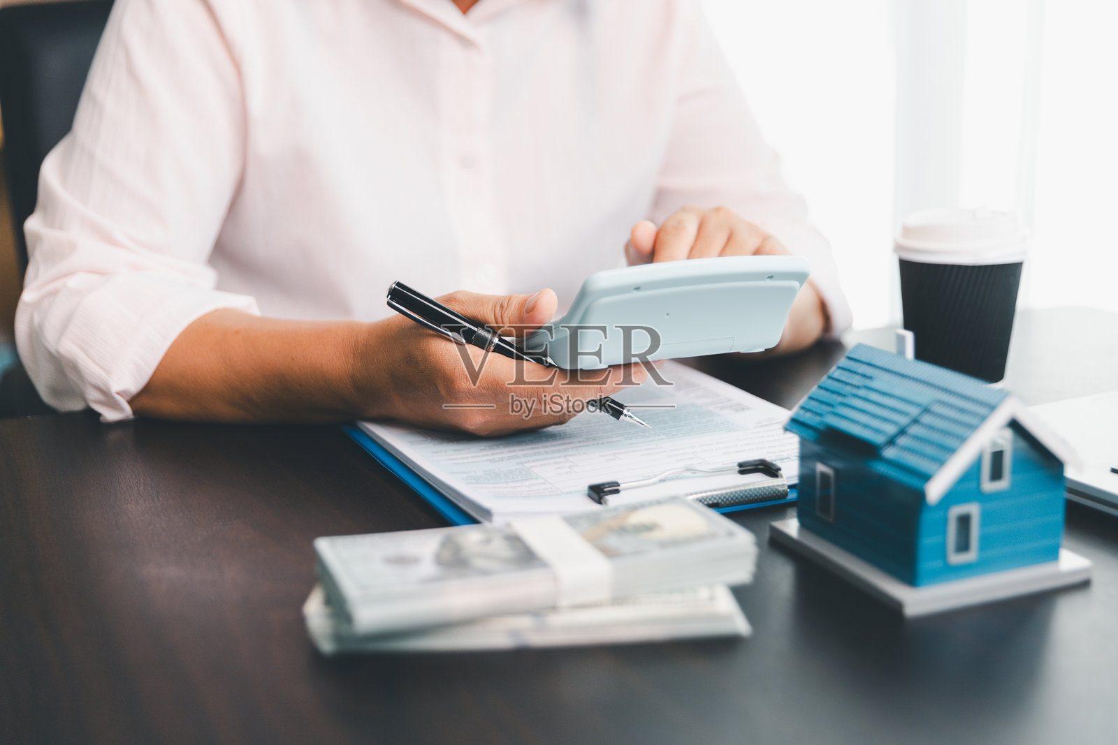 用于检查和总结房贷再融资计划费用的计算器,体现人们的生活方式概念。房产中介使用计算器为客户计算每月的贷款期限。照片摄影图片