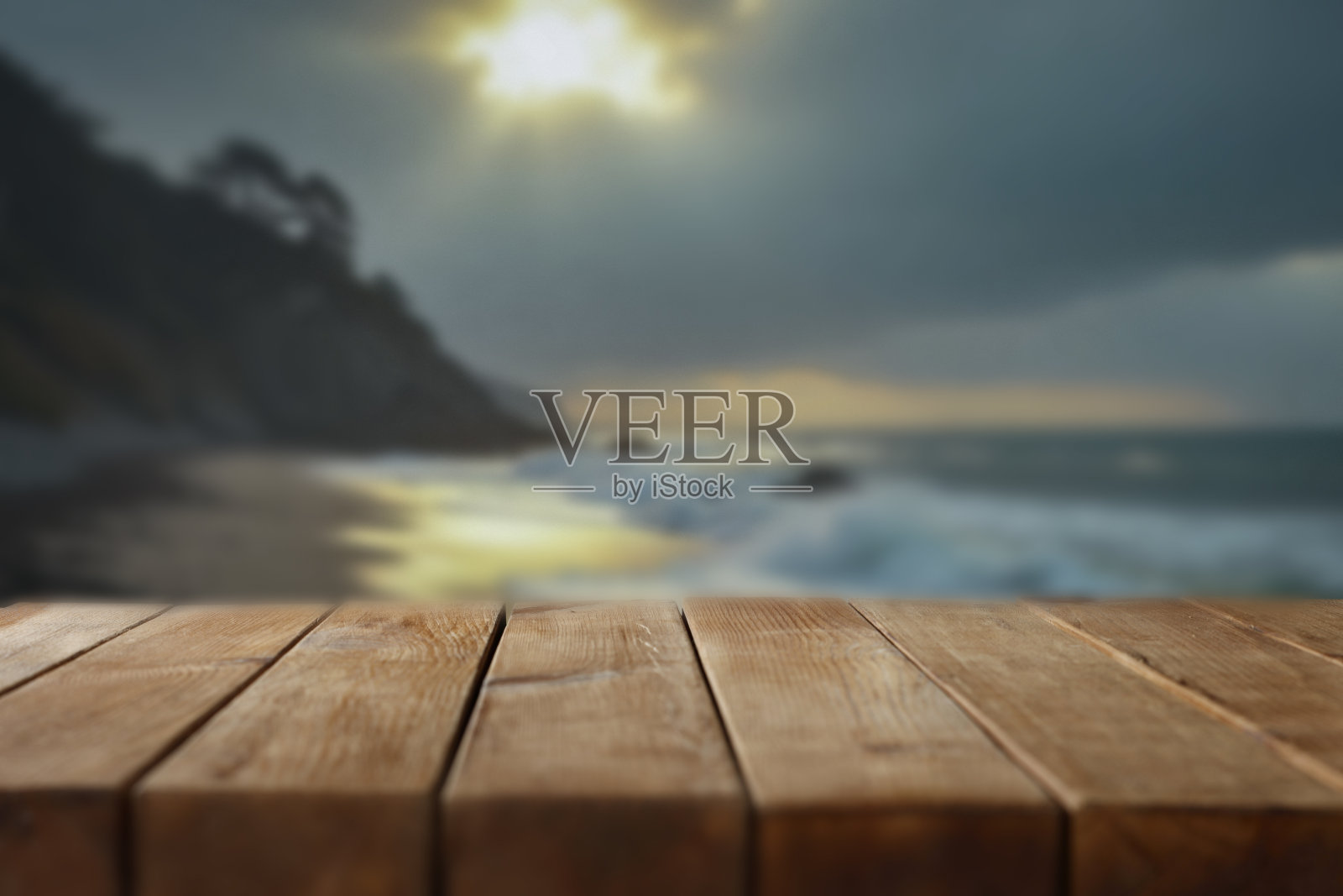 空的木桌,适合放置产品 - 背景模糊的海岸线,海洋、山脉和阳光明媚的天空。照片摄影图片