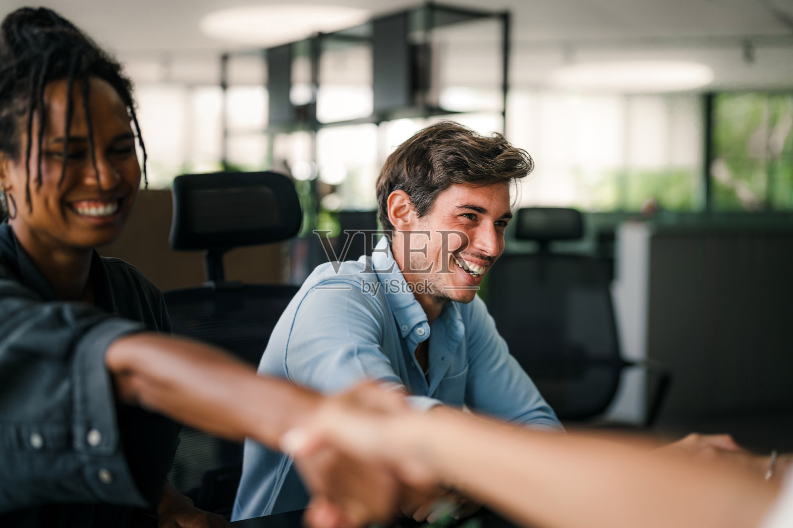 年轻的女商人与男商在办公室会议上愉快地握手照片摄影图片