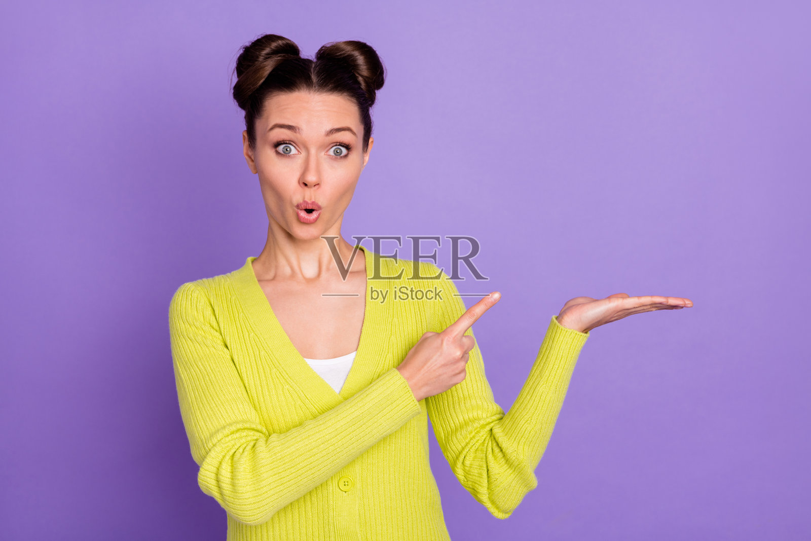 年轻女孩惊讶地指着,背景为紫色,适合广告产品的空白空间。照片摄影图片