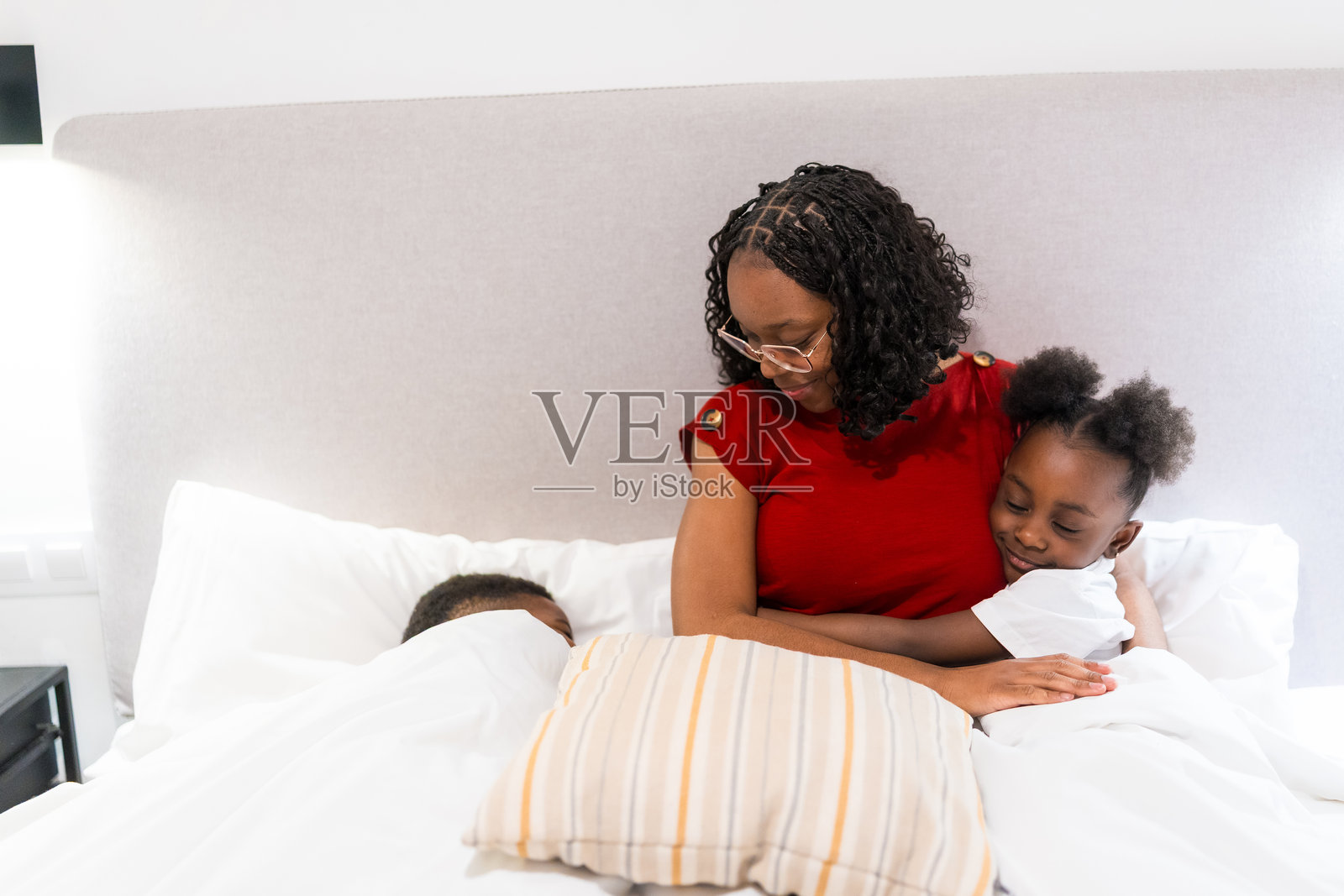 母亲在床上抱着女儿,哄孩子们入睡照片摄影图片