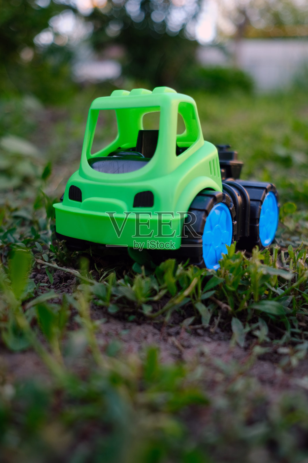 一辆明亮绿色的玩具卡车静静地停在郁郁葱葱的草地上,展现出其鲜艳的色彩。阳光照耀着这个场景,营造出一种适合户外冒险的愉快氛围。照片摄影图片