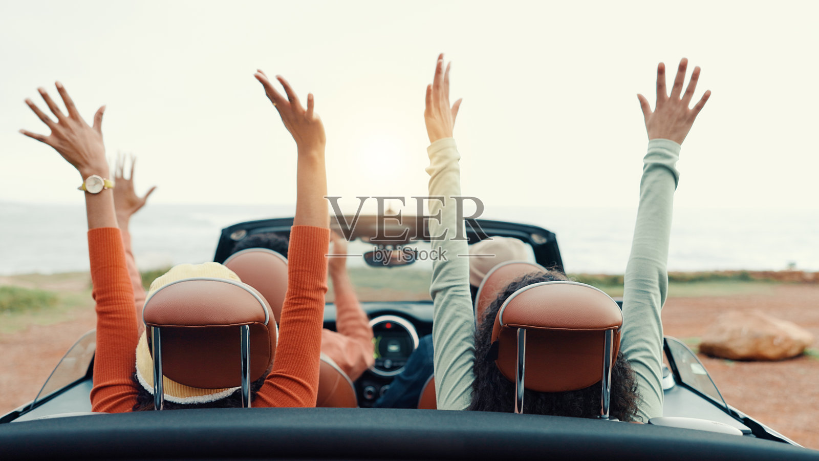 在公路旅行中,朋友们在车里兴奋地举起双手,享受团体的亲密时光,度假旅行。户外,充满活力的人们,交通工具或机动车辆象征着自由、冒险和旅游。照片摄影图片