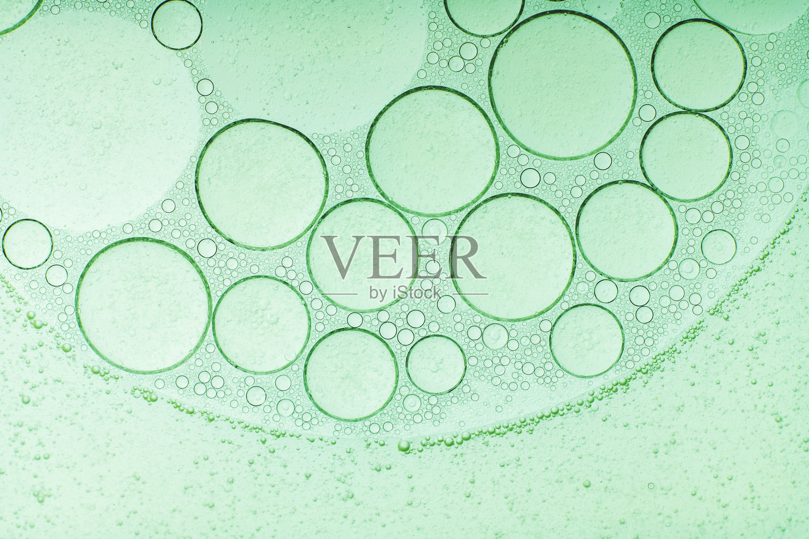 宏观显微镜绿色气泡纹理,特写绿色气泡和油滴背景。蓝绿色水泡,特写金色油滴用于化妆品。照片摄影图片