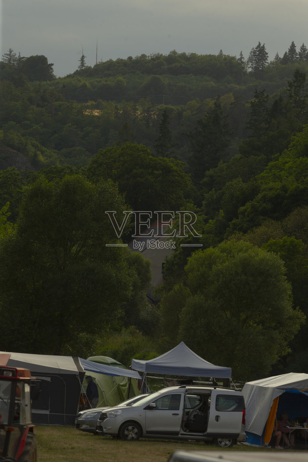 汽车和帐篷停在树木背景的田野中照片摄影图片