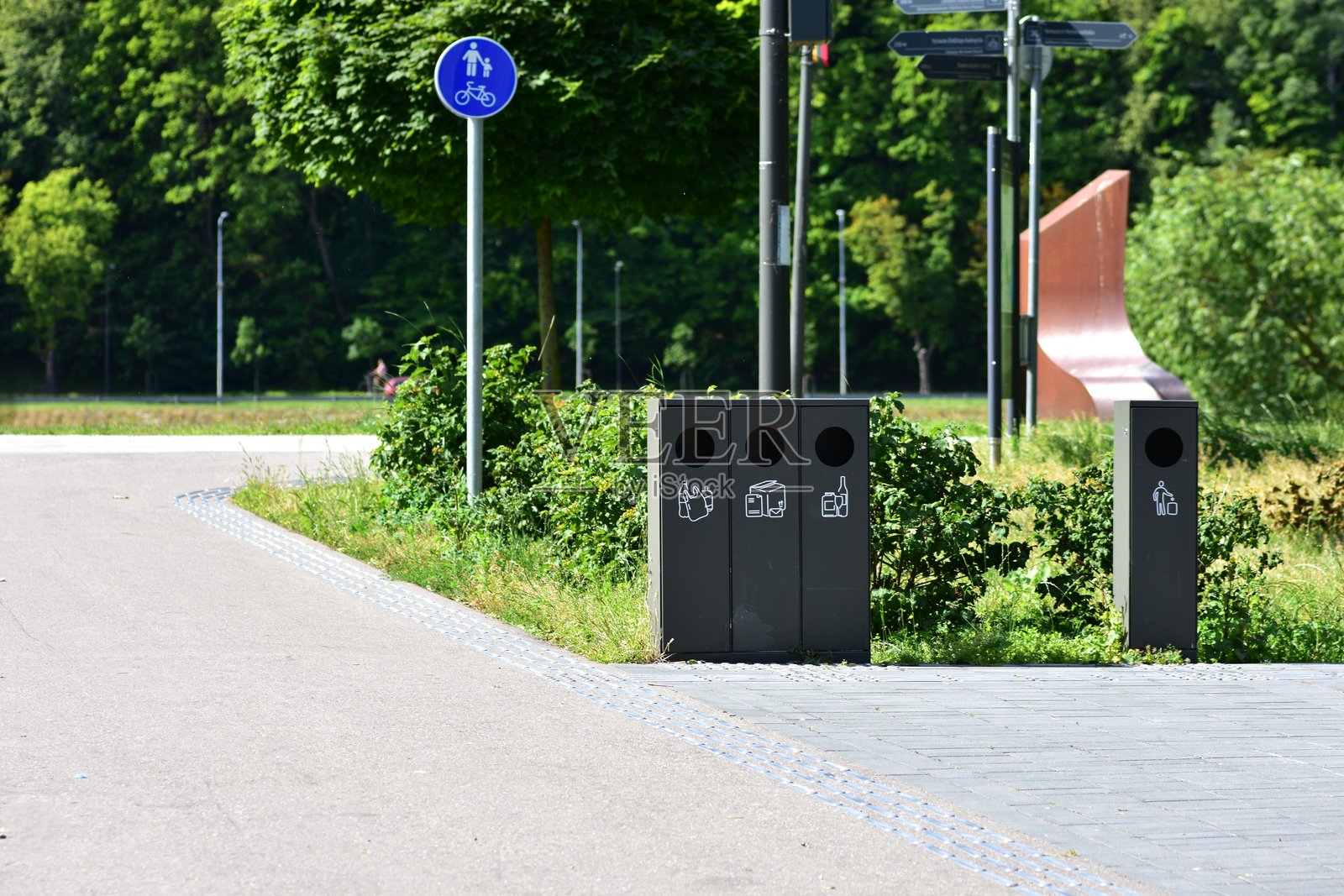 现代城市人行道旁的垃圾分类箱,靠近公园。环保回收站鼓励可持续发展和清洁公共空间。清晰的标签指导正确的垃圾处理。照片摄影图片