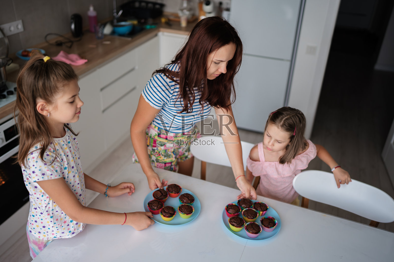 母亲和女儿们在厨房里一起烘焙自制杯子蛋糕照片摄影图片