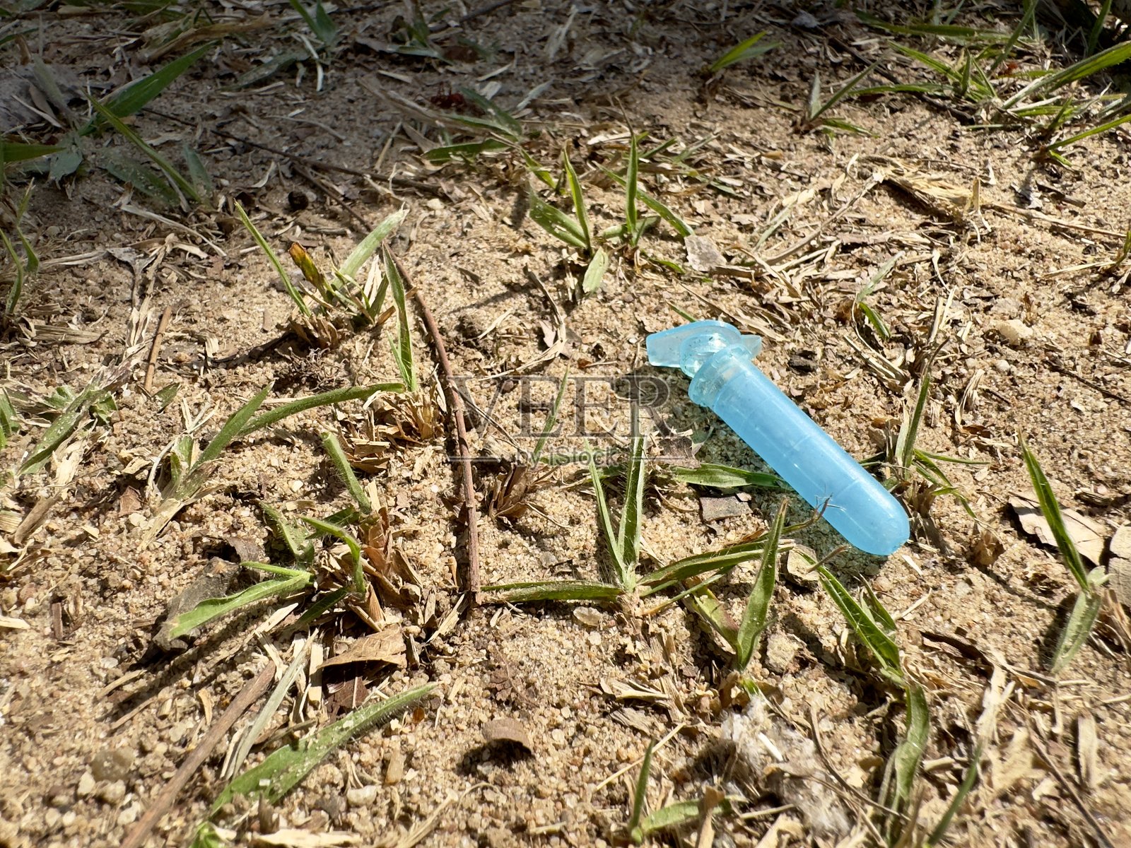 废弃的塑料管放置在干草覆盖的泥土地面上。关于污染、不规则废物处理、环境影响和生态意识的概念性图像。非常适合可持续发展宣传和环境教育。照片摄影图片