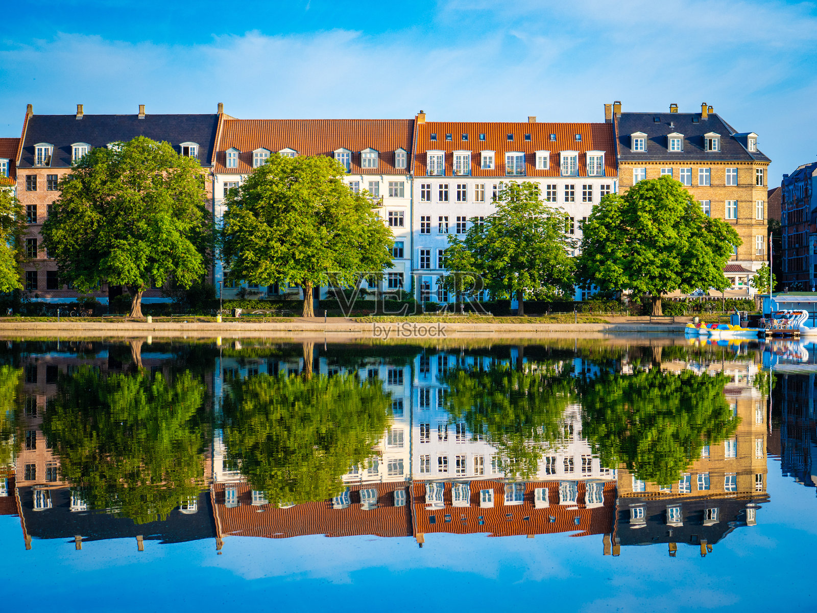 哥本哈根的佩布林湖在宁静的水面上映照出历史悠久的建筑立面和郁郁葱葱的树木。照片摄影图片