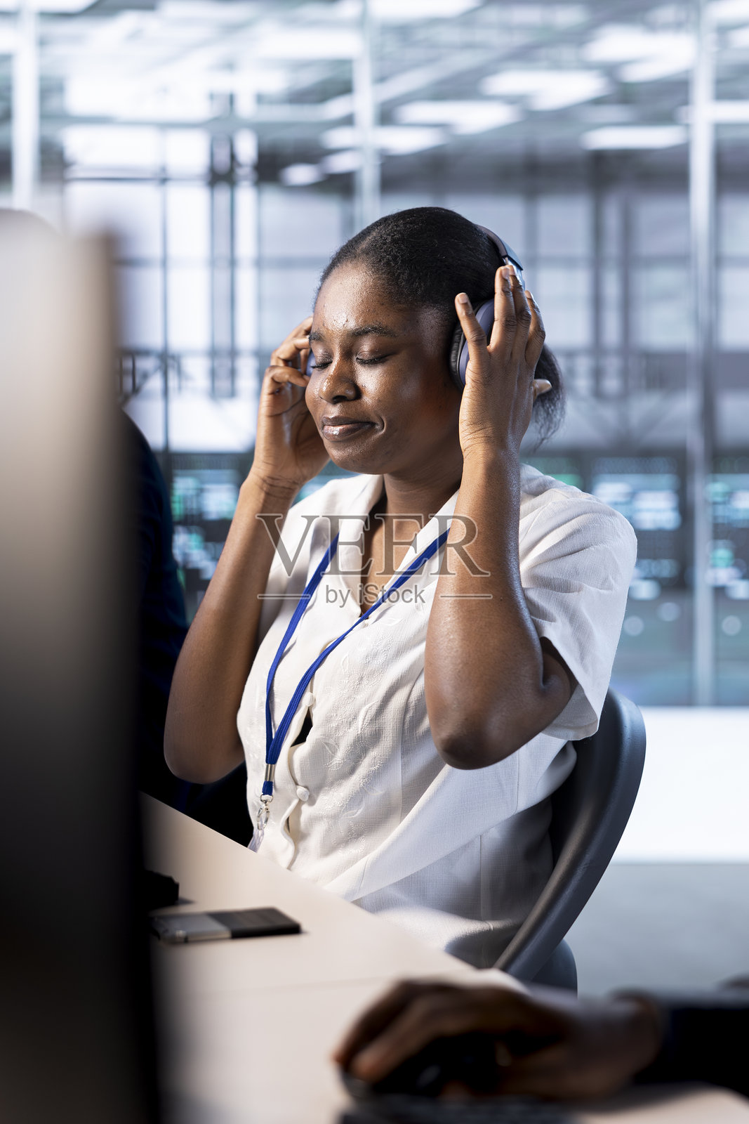 数据中心的管理员戴着耳机,享受音乐。照片摄影图片