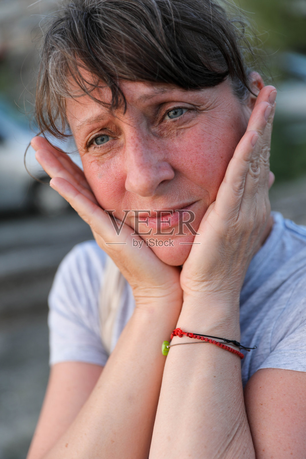 成熟的女性在户外轻柔地用双手托着自己的脸照片摄影图片