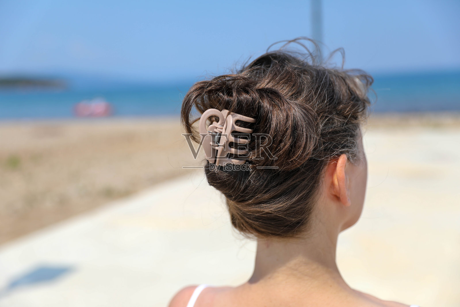 成熟的女性面朝大海,头发用夹子固定。照片摄影图片