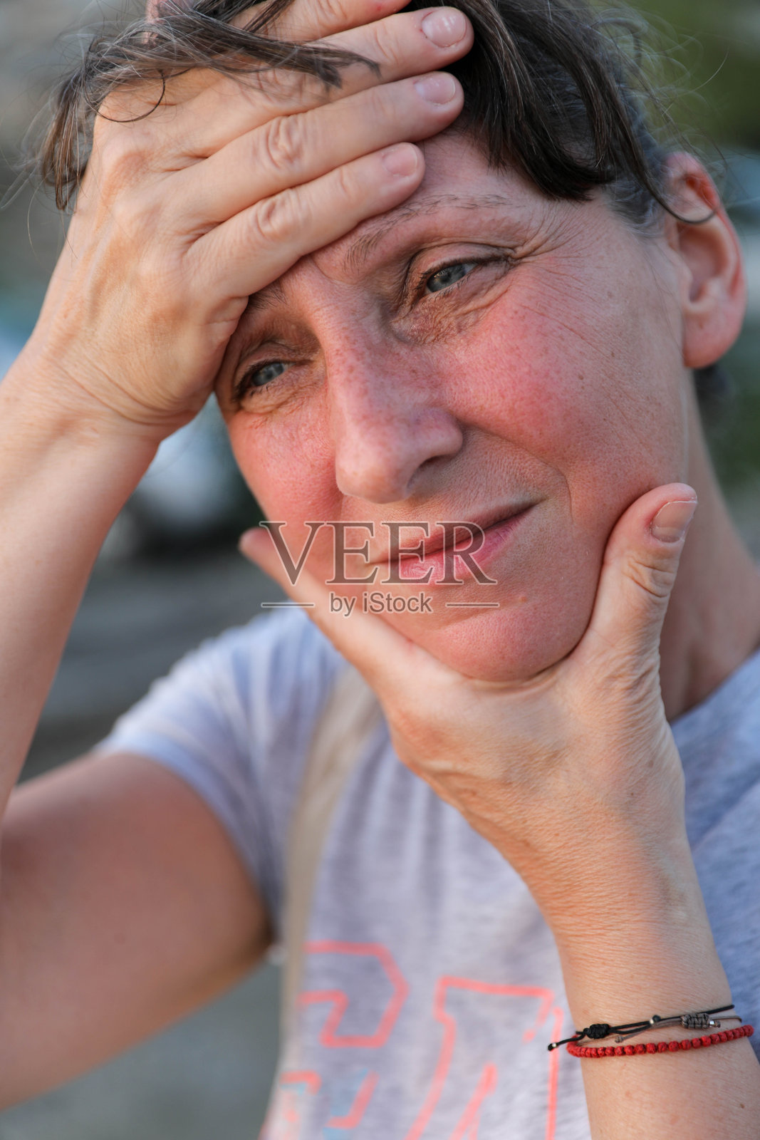 成熟的女性用关切的表情触摸额头和下巴照片摄影图片