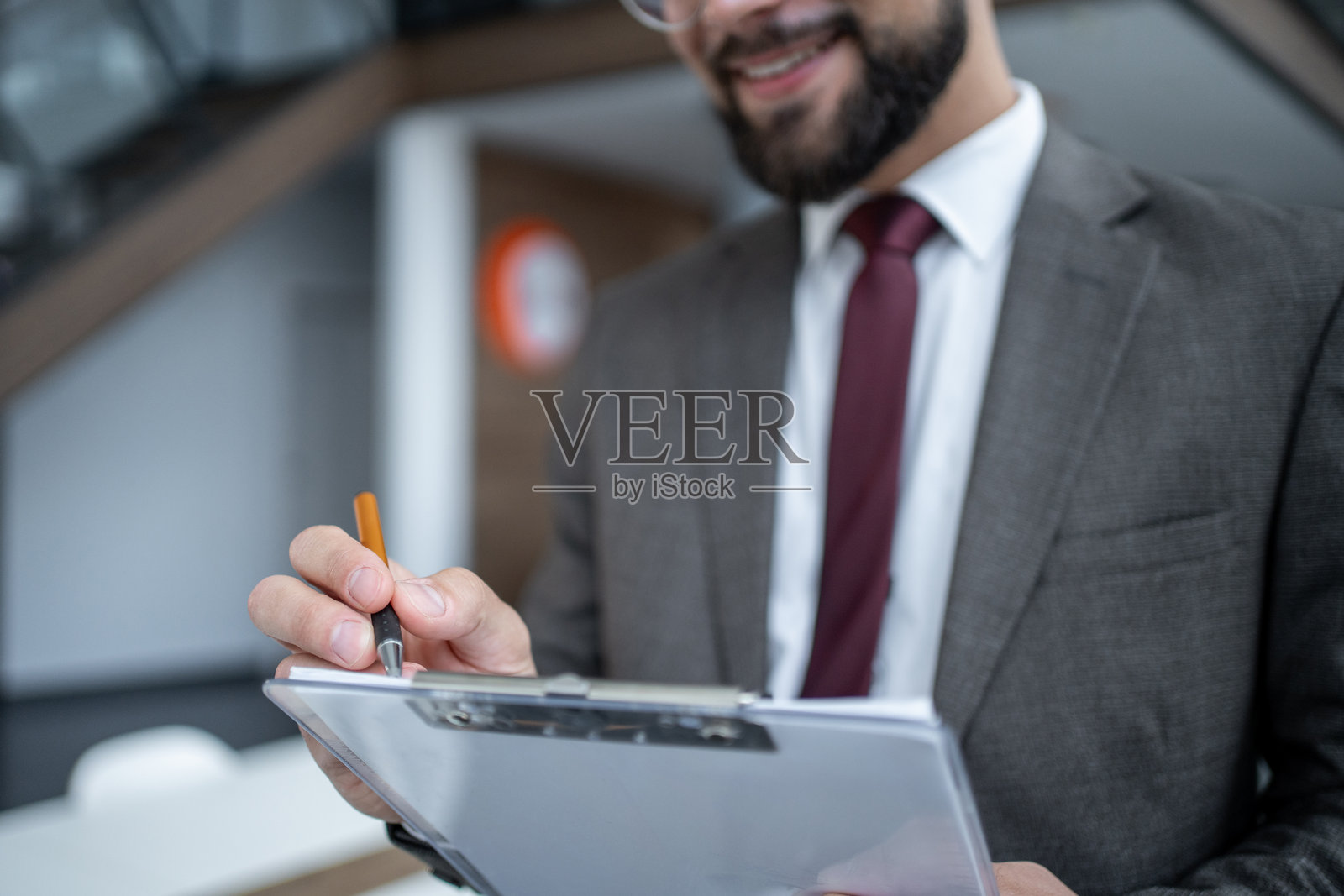 商人在办公室微笑着用夹板做笔记照片摄影图片