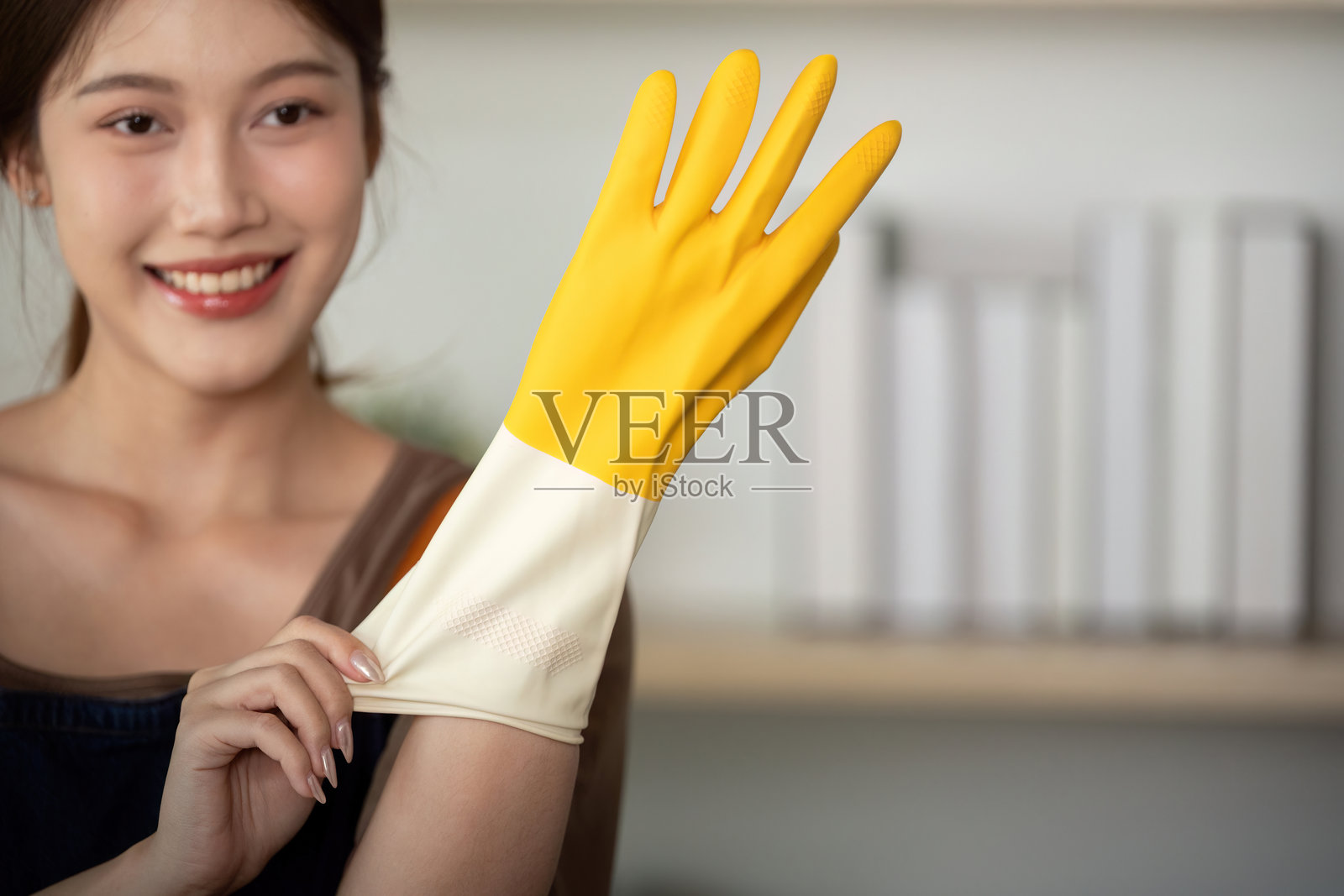 家庭清洁。微笑的女性戴着黄色橡胶手套,准备开始清洁。照片摄影图片