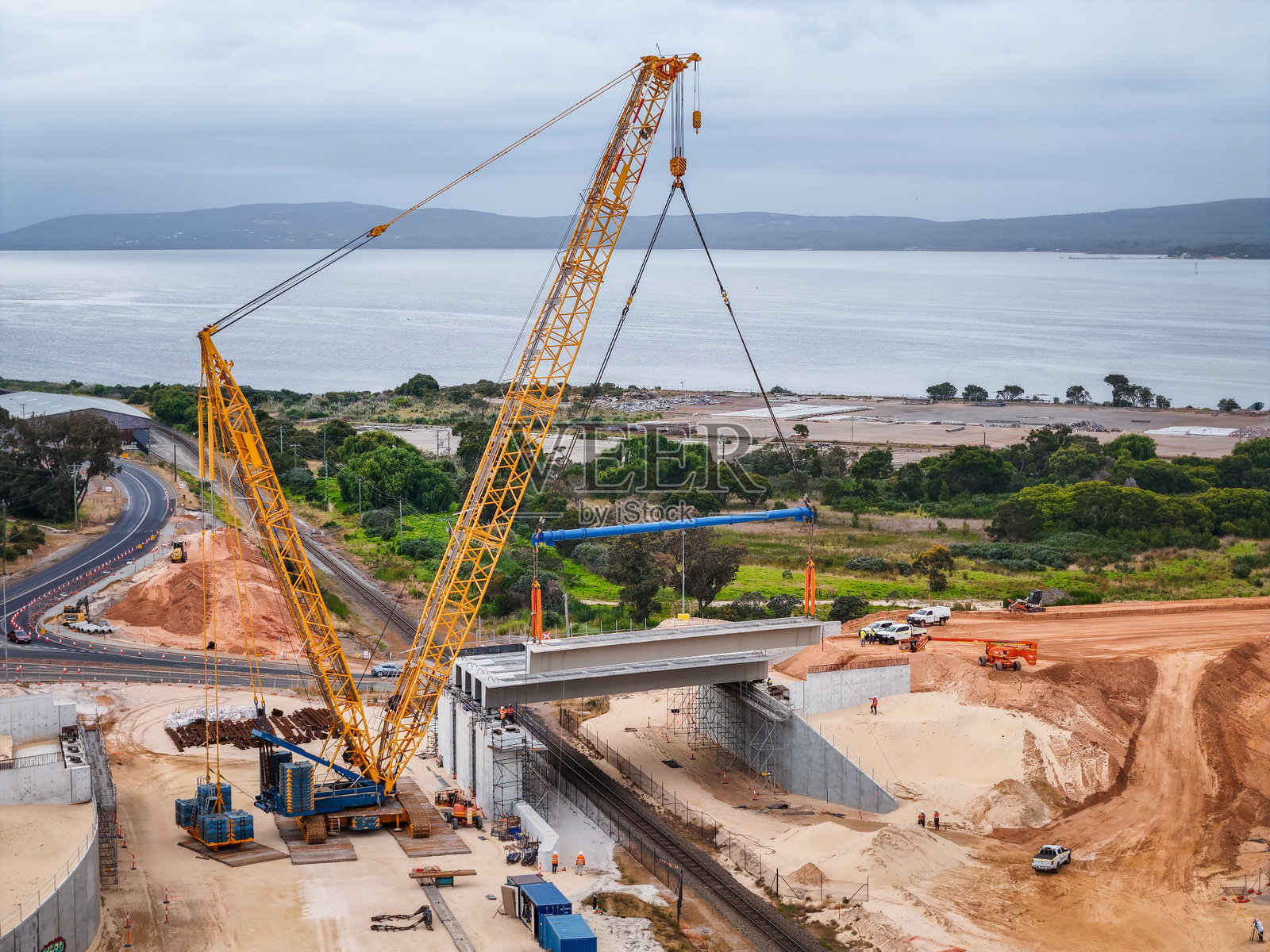大型建筑起重机在风景如画的水滨景观中组装桥梁照片摄影图片