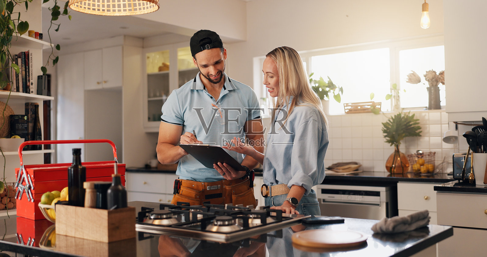 女人、男人和持有夹板的水管工在家中讨论维修厨房的发票和报告。人们、手艺人和客户在公寓中微笑着检查排水系统的清单。照片摄影图片