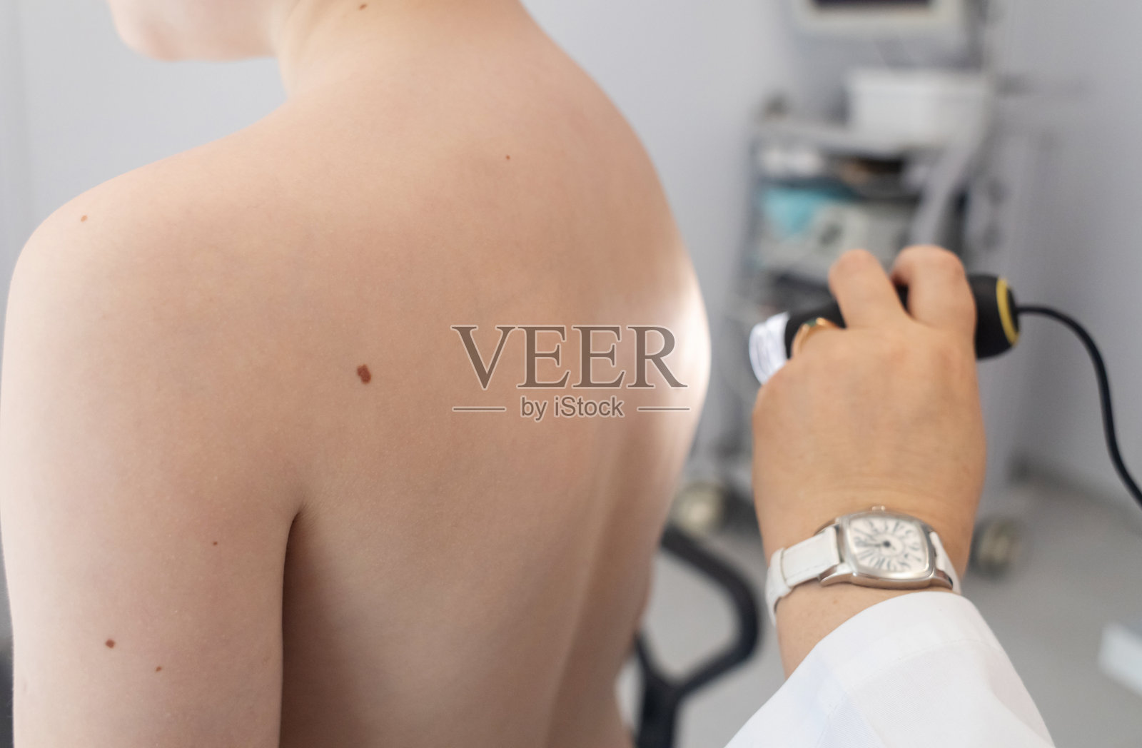 一位儿科皮肤科医生在医疗诊所使用皮肤镜检查小男孩的皮肤,进行痣和胎记的皮肤检查。照片摄影图片