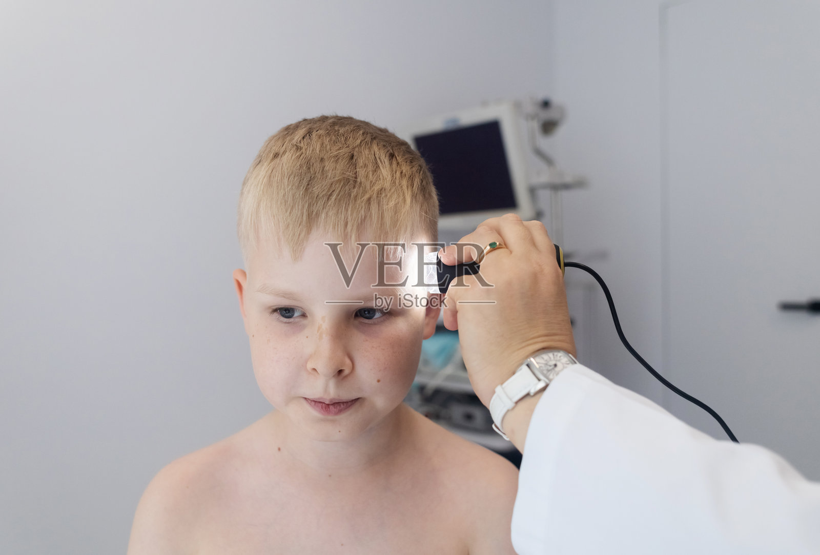 一位儿科皮肤科医生在医疗诊所使用皮肤镜检查小男孩的皮肤。对痣和胎记进行皮肤检查。照片摄影图片