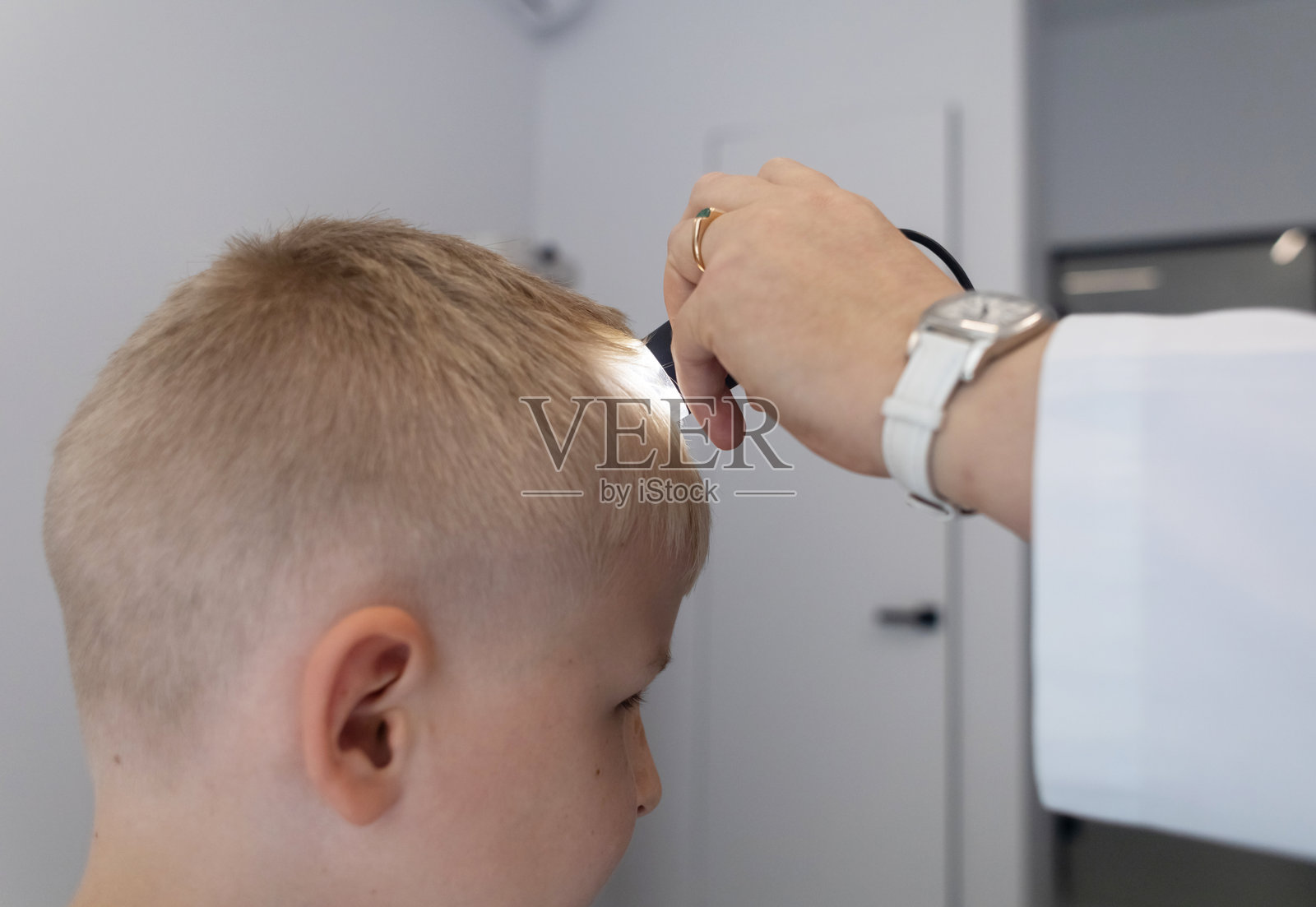 一位儿科皮肤科医生在医疗诊所使用皮肤镜检查小男孩的皮肤。进行痣和胎记的皮肤检查。照片摄影图片