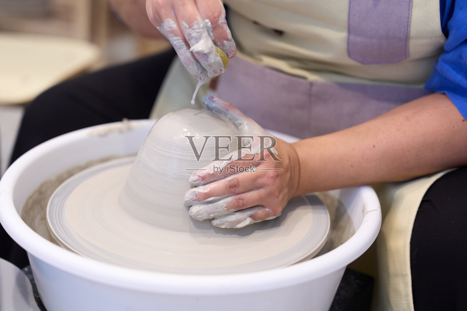 陶艺师在陶轮上用海绵制作陶瓷器皿照片摄影图片