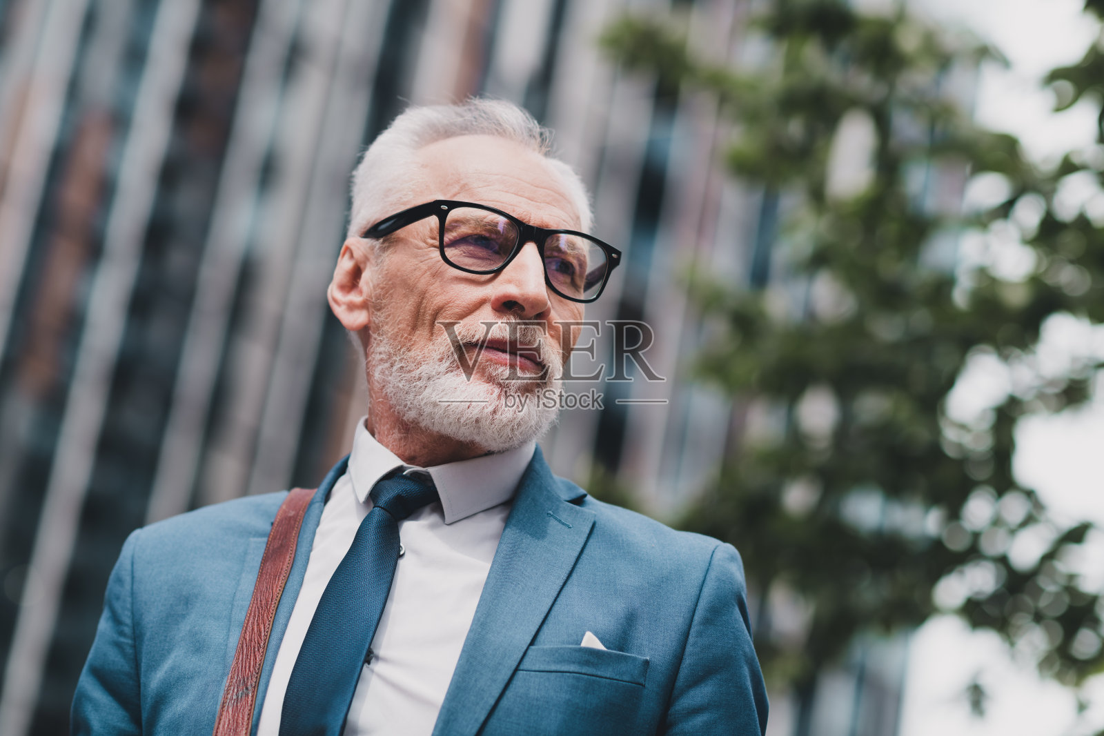 自信的成熟商人在城市环境中走动,身穿正式的蓝色西装,散发出专业和领导的气场照片摄影图片