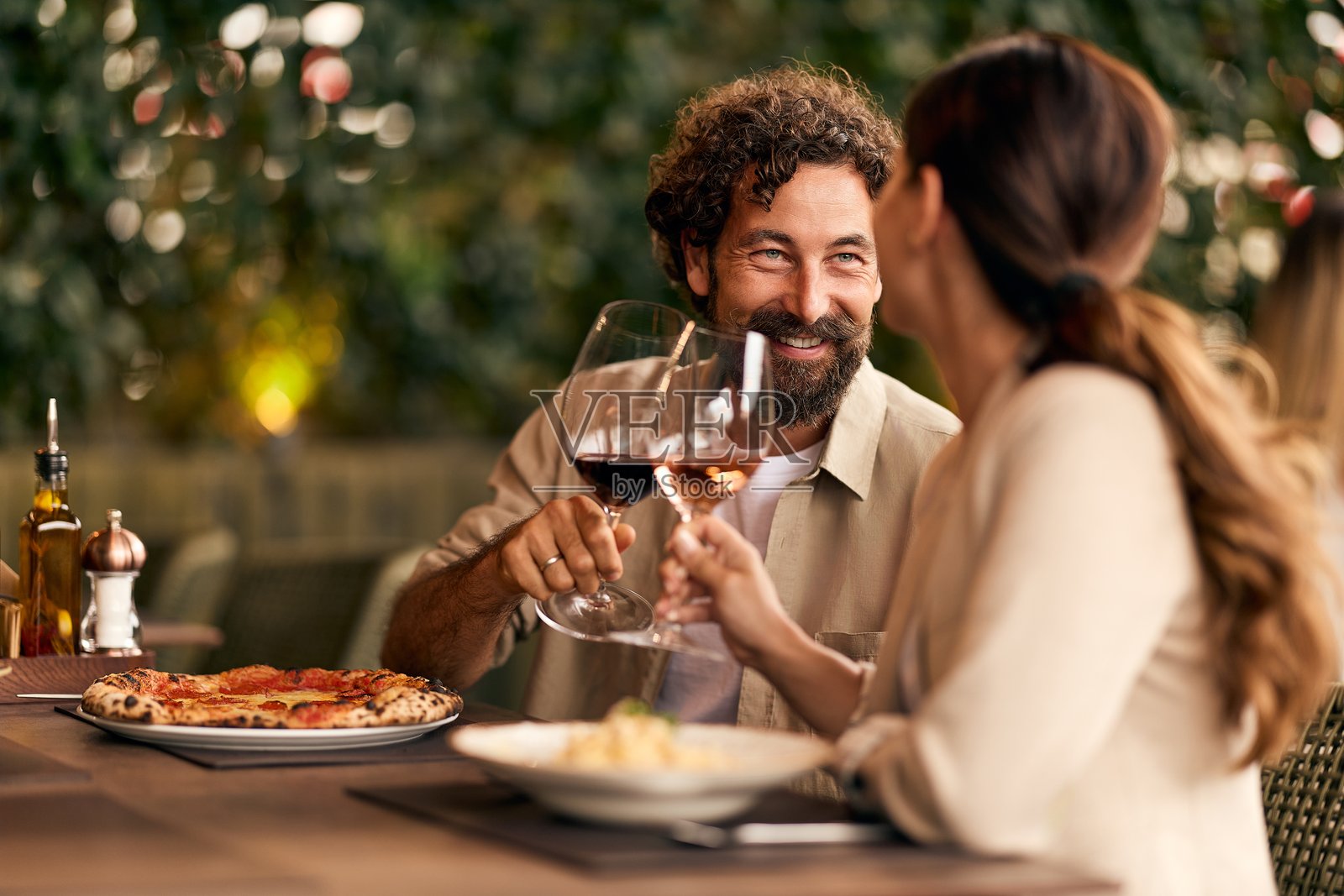 微笑的情侣在温馨的餐厅享受浪漫晚餐,手中举着酒杯照片摄影图片