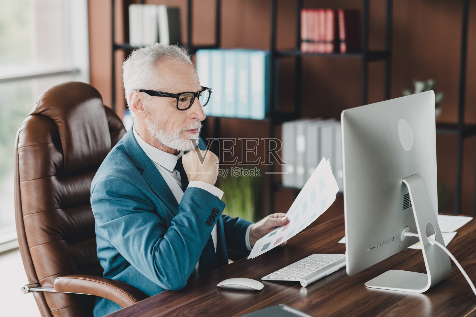 高级商务人士在现代办公室工作区的桌子上审阅财务文件照片摄影图片