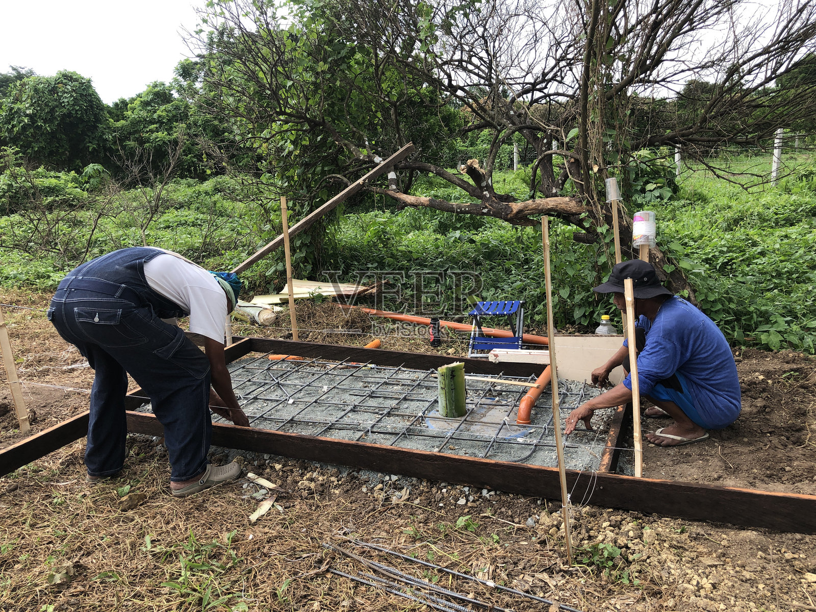 建筑工人正在将混凝土混合物倒在化粪池的底板上。照片摄影图片