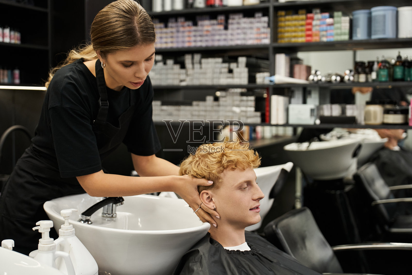 年轻的造型师在现代美容沙龙为帅气的客户提供放松的护发护理照片摄影图片