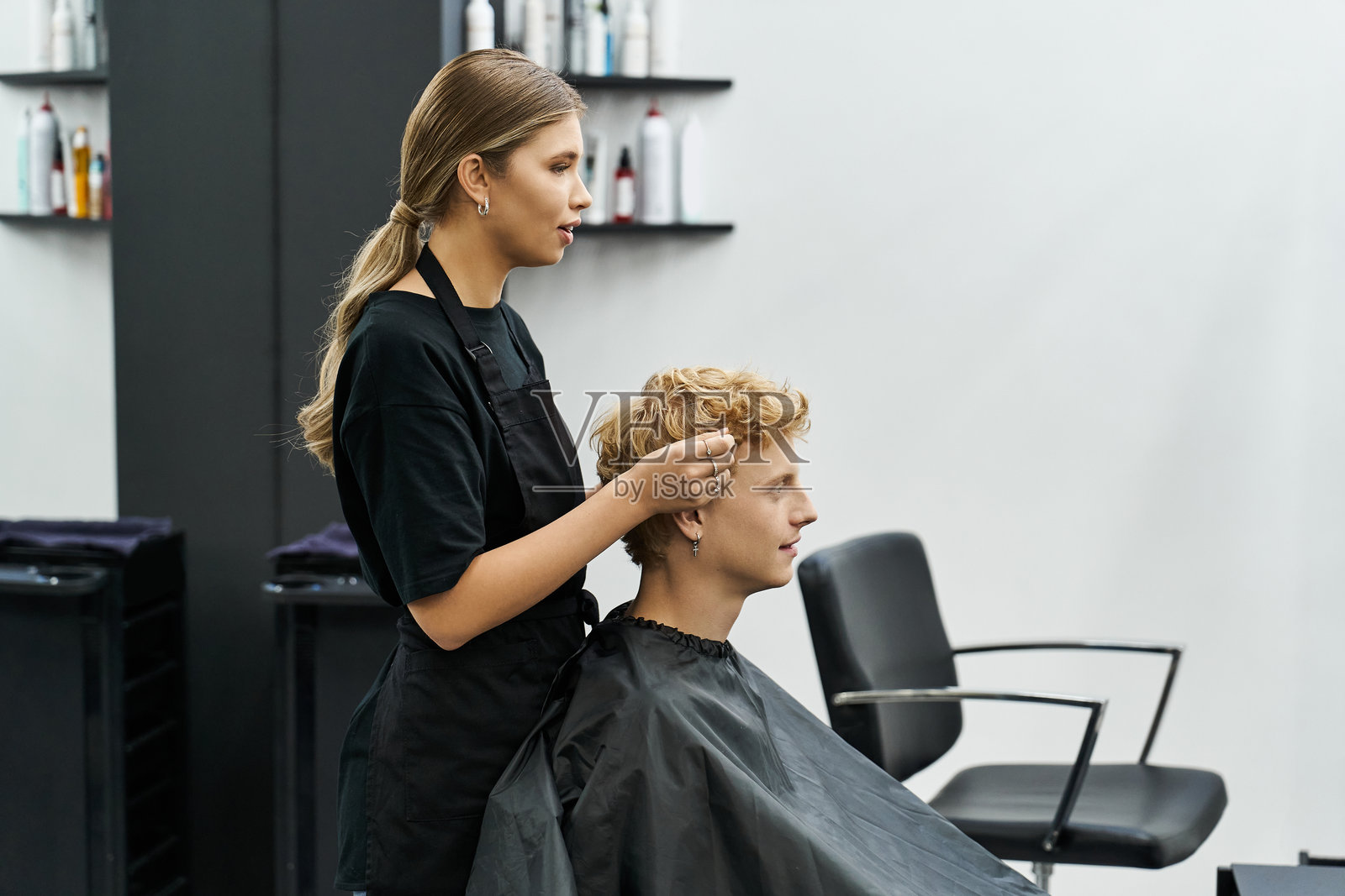 发型师在充满活力的美容沙龙氛围中专注地为年轻男子设计发型照片摄影图片