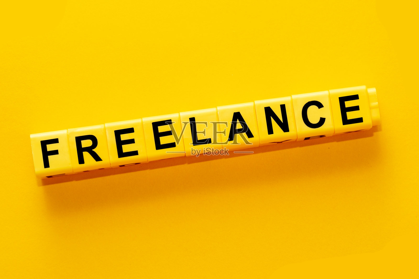 用黄色塑料积木拼出的“自由职业”字样。照片摄影图片