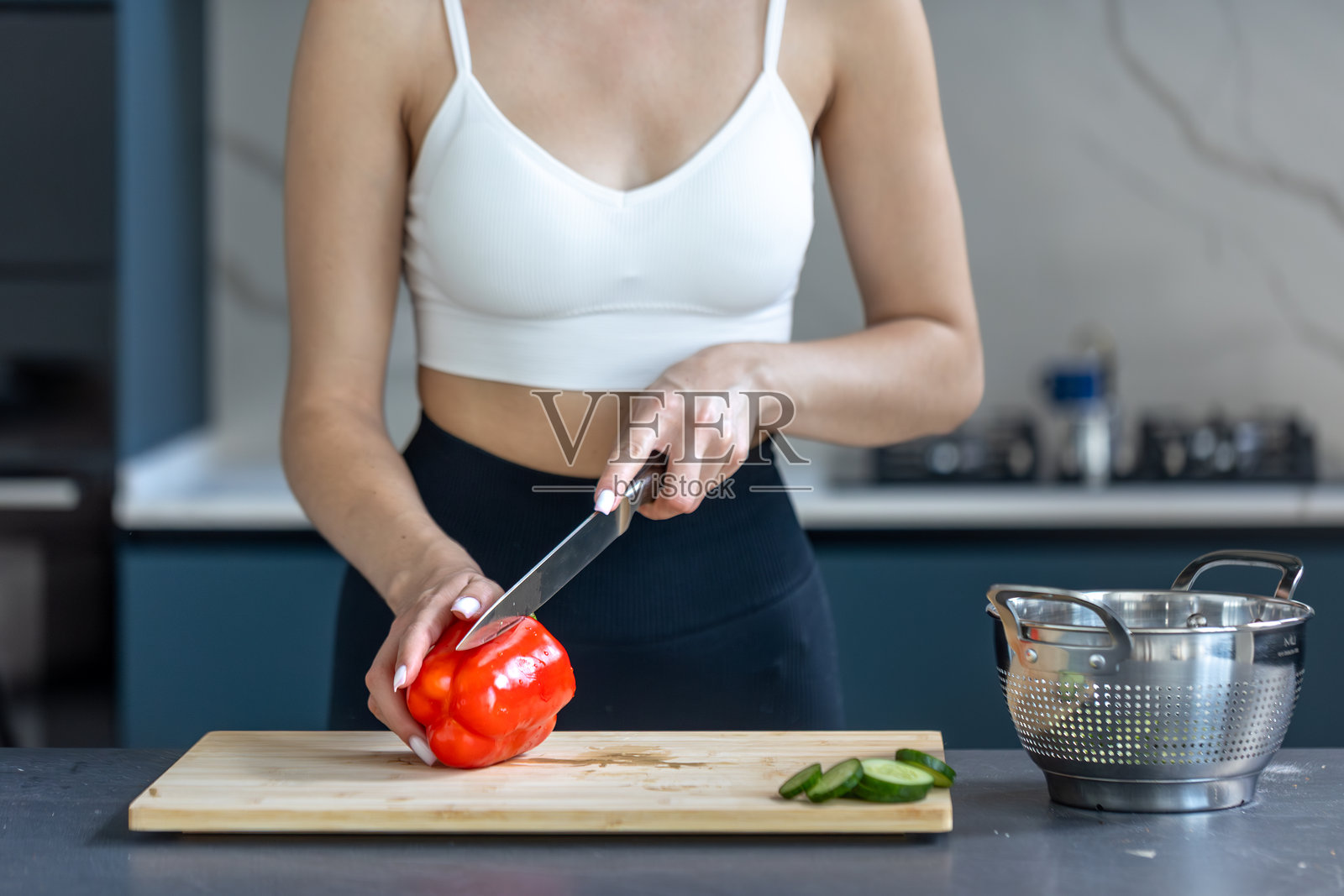 女人在准备沙拉。红椒和黄瓜。厨房氛围。照片摄影图片